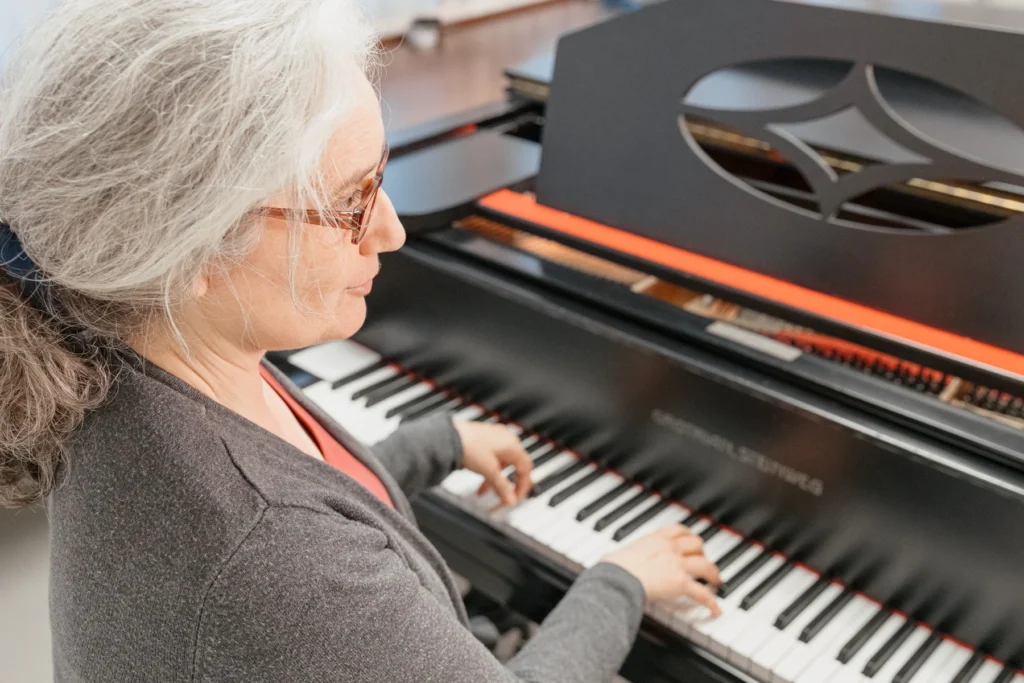 Eine Gesangspädagogin sitzt am Klavier und begleitet eine nicht sichtbare Person